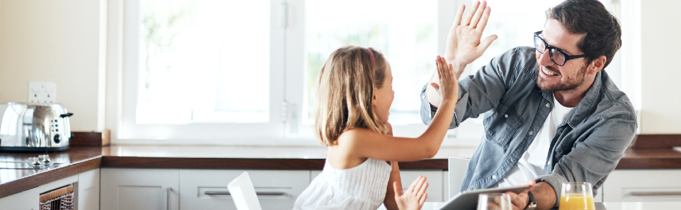 Father and young girl sharing a high five in the kitchen